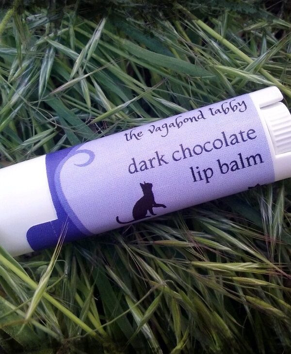 A white lip balm tube; the label says 'dark chocolate'.