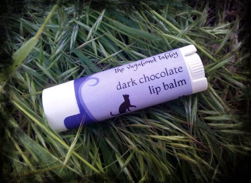 A white lip balm tube; the label says 'dark chocolate'.