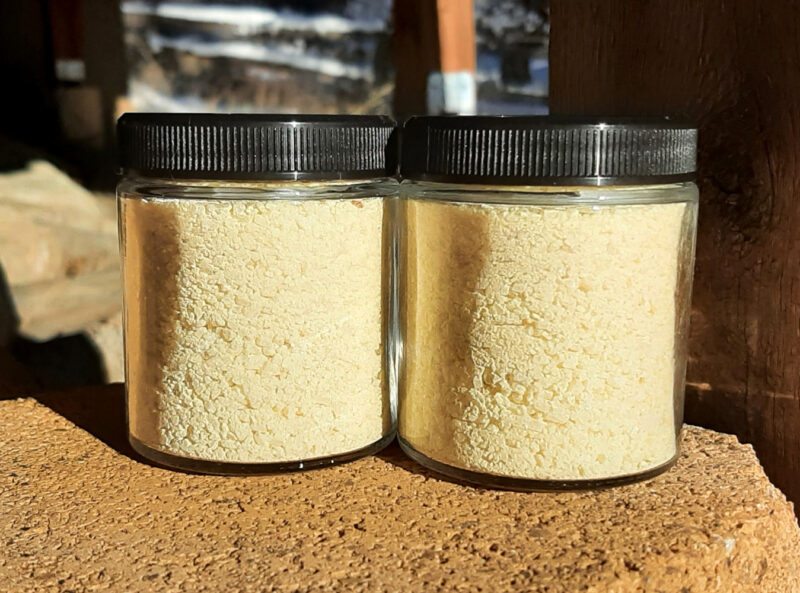 Two clear glass jars are filled with yellow bath salts.