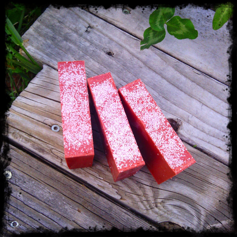 Three bars of red soap, with white sea salt sprinkled on top.