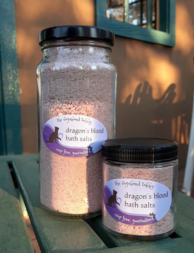 Two clear glass jars filled with reddish-brown bath salts. One is much taller than the other.