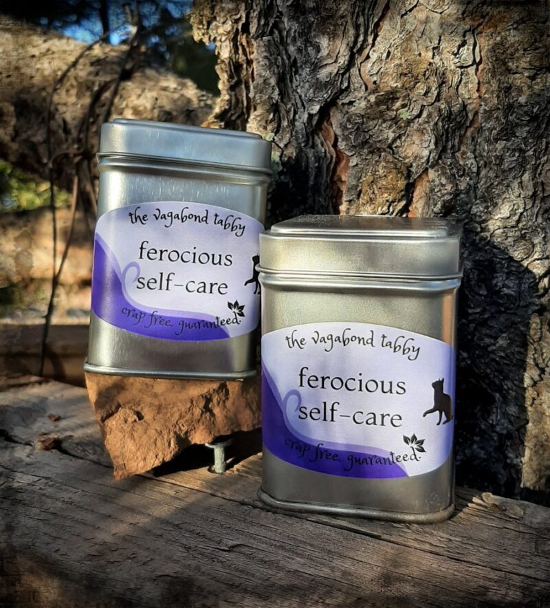Two stainless steel tea tins; the labels say "ferocious self-care".