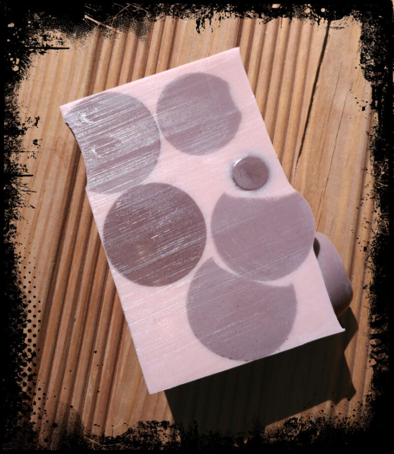 A single bar of soap, medium brown with dark brown spheres embedded in it.