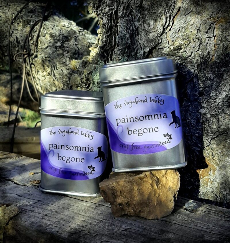 Two stainless steel tea tins; the labels say "painsomnia begone".