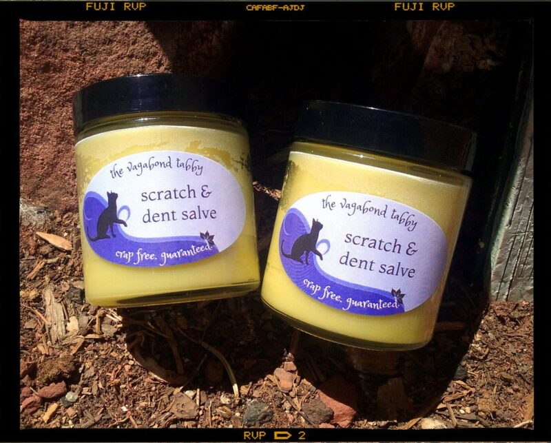 Two big clear glass jars filled with pale yellow salve. The labels say 'scratch & dent salve'.
