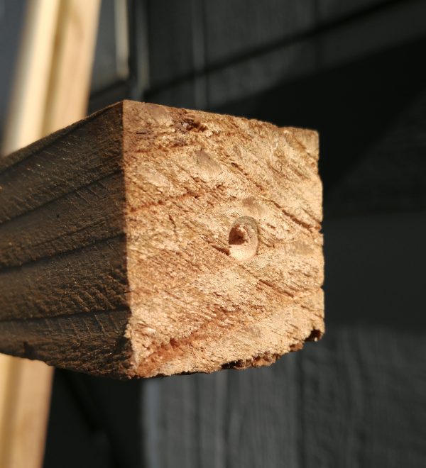 The end of a 2x2 wooden pole, with a small hole banged into the center of it. That's where the drill bit goes.