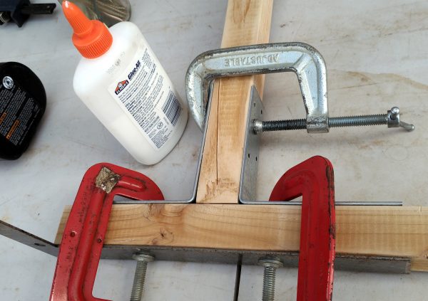 A pair of 2x2 wood boards, held quite firmly at right angles by a variety of clamps & things. Also there's a bottle of glue, which has, presumably, actually been used on the wood.