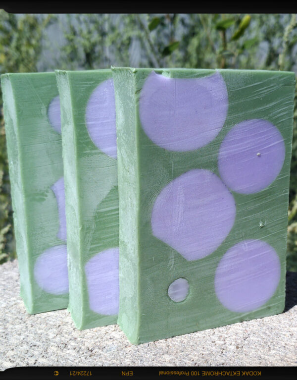 Three bars of soap, green with purple spheres embedded in them.
