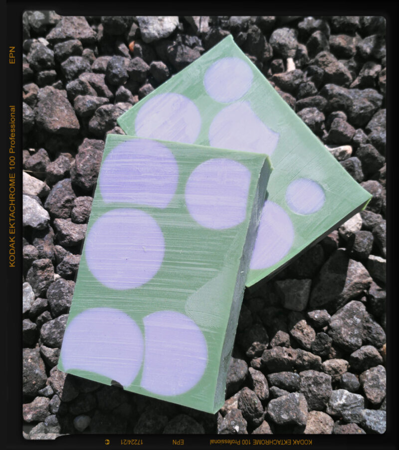 Two bars of soap, green with purple spheres embedded in them.
