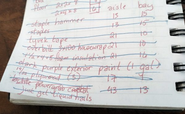 A notebook with a shopping list written on it in dark pink pen. It contains items like 'tyvek tape' & '19/32 plywood'. Everything on the list has been crossed out in light blue.