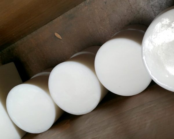 A bunch of round bars of soap on a wooden shelf.