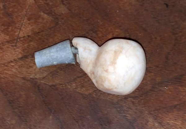 The bowl of the pipe is very round, & it's cut from a peachy-white stone. The stem is short & cut from a light grey stone.