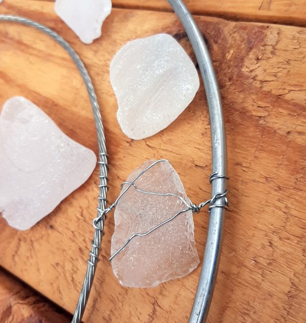 The smallest seaglass piece has been wrapped in thin silvery wire, which extends to fasten it between the hoop & the thick wire.