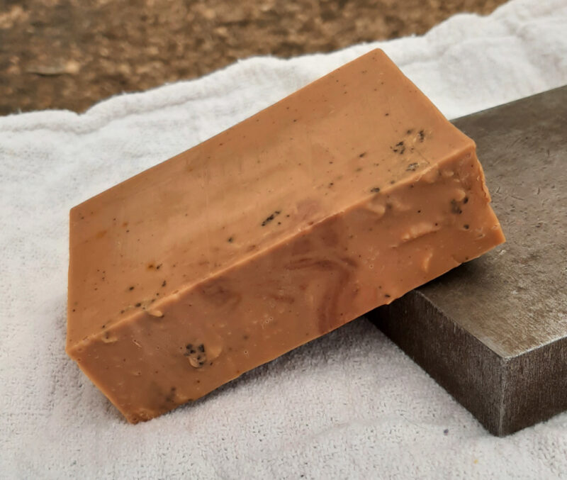 A bar of brown soap, speckled with ground coffee.