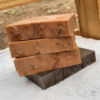 Three bars of brown soap, speckled with ground coffee.