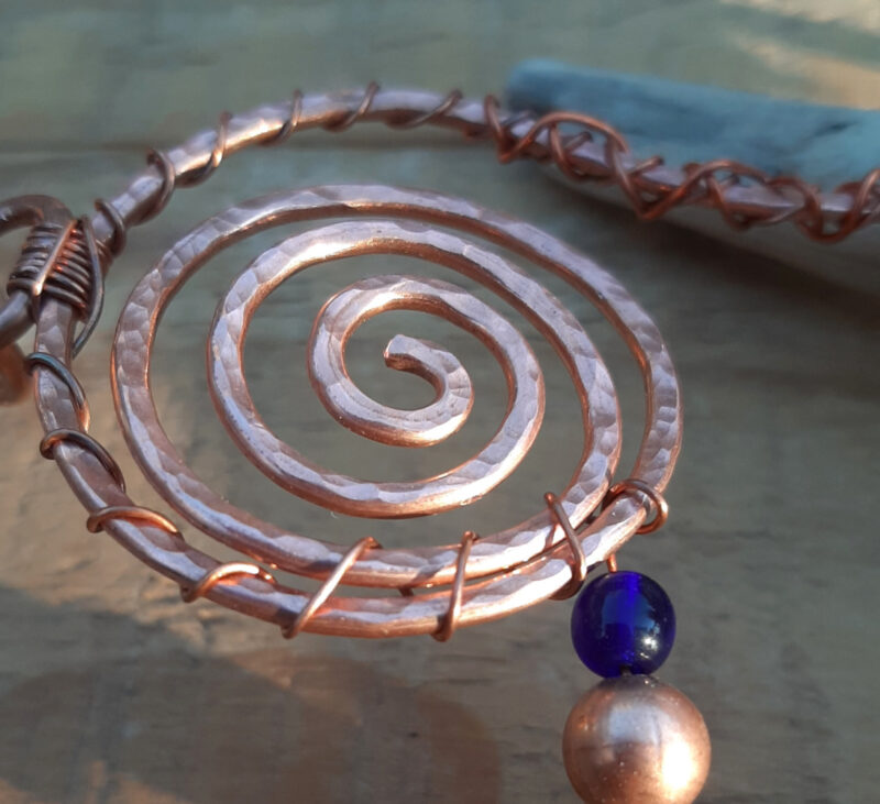 A broader spiral, wound out and back again with fine copper wire. Beads spring from the edge.