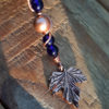 Another strand of beads, strung on copper wire that doubles back and around the beads it holds fixed. A maple leaf marks the end.
