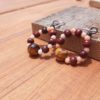 Each earring is a loop strung with alternating tiny peach beads and slightly bigger red wooden ones, with a larger stripey brown and gold bead at the bottom.