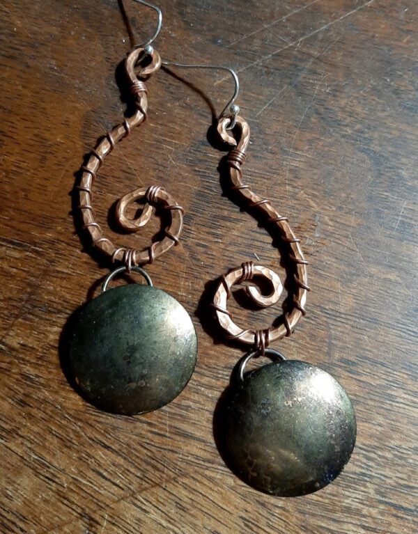 Each earring is hammered copper wire shaped like an inverted question mark. From the bottom hangs a domed brass circle, weathered til it looks a bit like a moon.