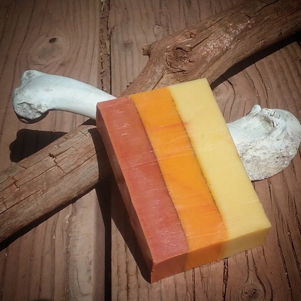 A single bar of soap, colored in three layers: red, orange, and yellow.