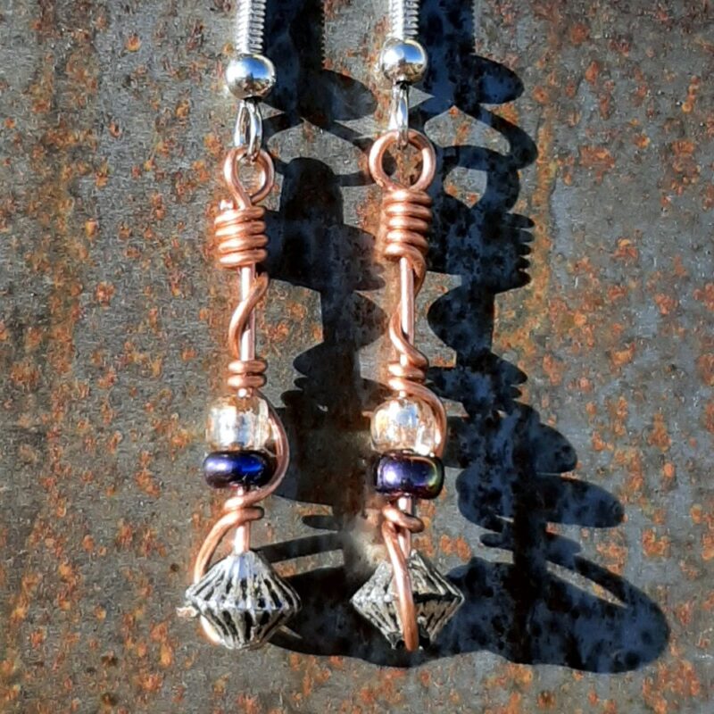 Each earring has a bicone silver-colored bead with an iridescent purple and a clear yellow glass bead above, all strung on copper wire that curves back up around each bead, then twists around itself.