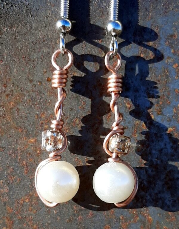 Each earring has a round white bead with a clear yellow glass bead above, all strung on copper wire that curves back up around each bead, then twists around itself.
