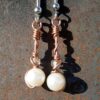 Each earring has a round white bead with a clear glass bead above, all strung on copper wire that curves back up around each bead, then twists around itself.