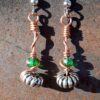 Each earring has an oval silver-colored bead with a green glass bead above, all strung on copper wire that curves back up around each bead, then twists around itself.