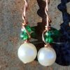 Each earring has round white beads with two oval green glass above, strung on copper wire that curves back up around each bead, then twists around itself.