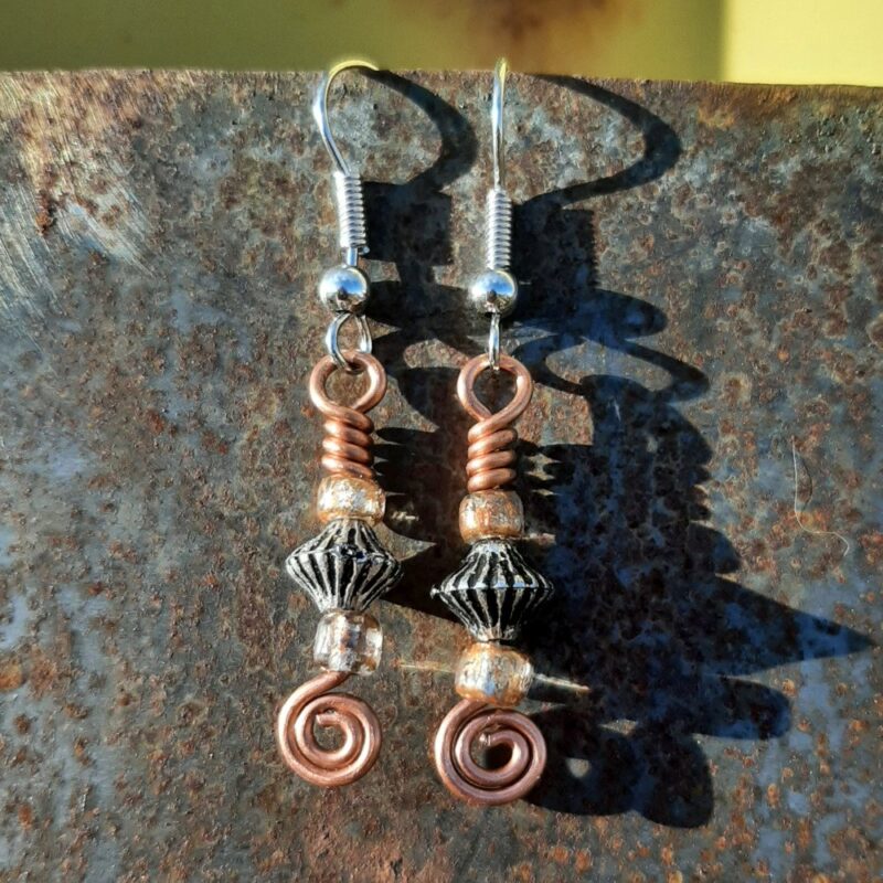 Each earring has a biconic silver-colored bead between two sparkly brown-orange beads, all strung on copper wire that ends at the bottom in a neat spiral.