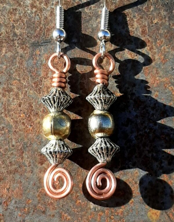 Each earring has a round brass bead between two biconic silver-colored beads, all strung on copper wire that ends at the bottom in a neat spiral.