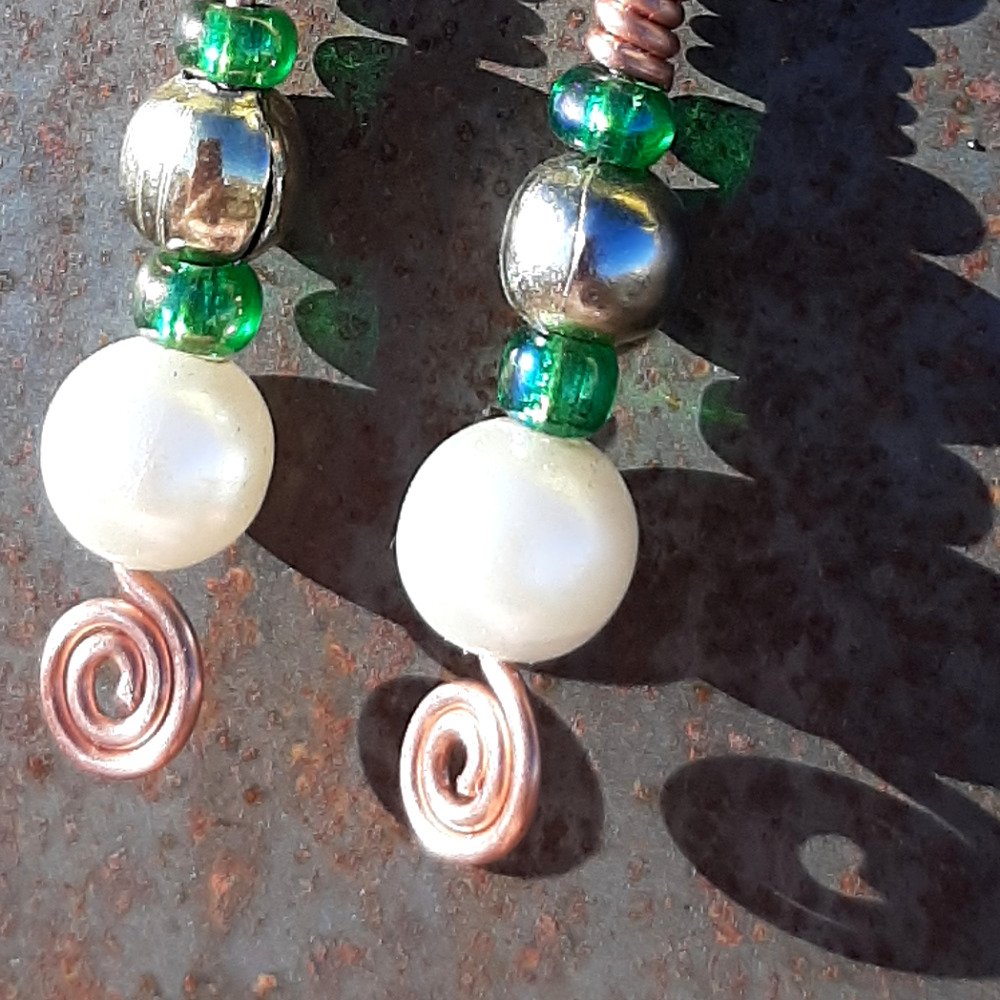 Each earring has, from bottom to top, a round white bead, a kelly green bead, a brass bead, and another kelly green one, all strung on copper wire that ends at the bottom in a neat spiral.