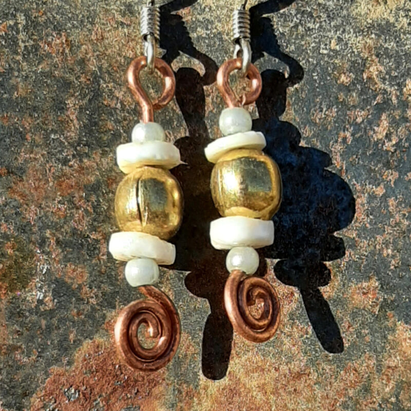 Each earring has a round brass bead with a disc-shaped bone bead above and below, and a small round pale blue bead to either side of those. All are strung on copper wire that ends at the bottom in a neat spiral.