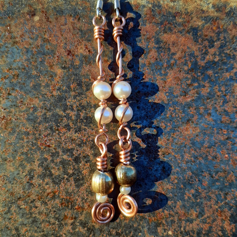 Each earring has two sections. The lower has a round brass bead with a much smaller white bead below it, both strung on copper wire with a neat spiral at the bottom. This is linked to a piece with two larger white beads strung on copper wire that curves back up around the beads, then twists around itself.