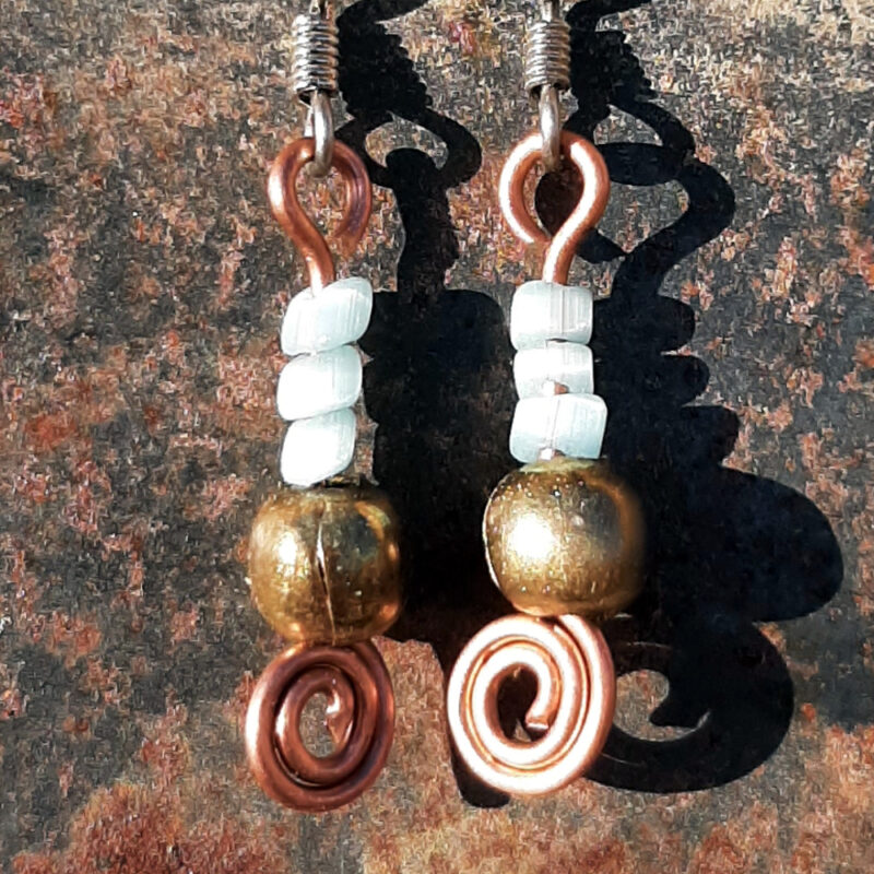 Each earring has a round brass bead with three pale blue beads above it. All are strung on copper wire that ends at the bottom in a neat spiral.