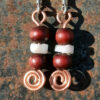 Each earring has two round red wooden beads with a disc-shaped bone bead in between. All are strung on copper wire that ends at the bottom in a neat spiral.
