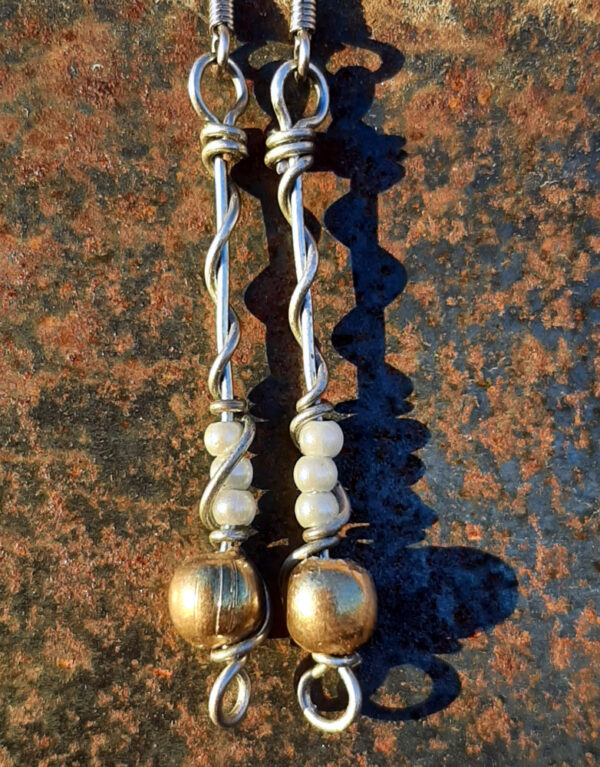 Each earring has a round brass bead with three smaller pale blue beads above it, all strung on steel wire that curves back up around each bead, then twists around itself.