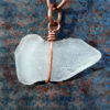 An oblong piece of white creek glass, simply wrapped, top to bottom, in copper wire.