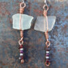 Each earring has a roughly rectangular piece of white creek glass, simply wrapped in copper wire, from which hangs another short length of copper with purple and silver-colored beads threaded onto it.