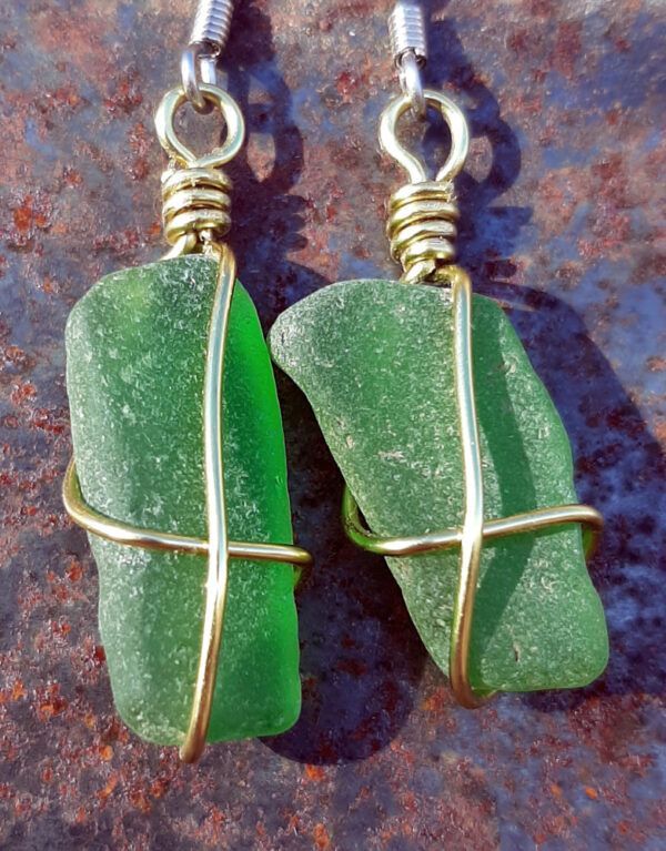 Each earring is a roughly rectangular piece of green creek glass, long way vertical, simply wrapped in gold-colored wire.