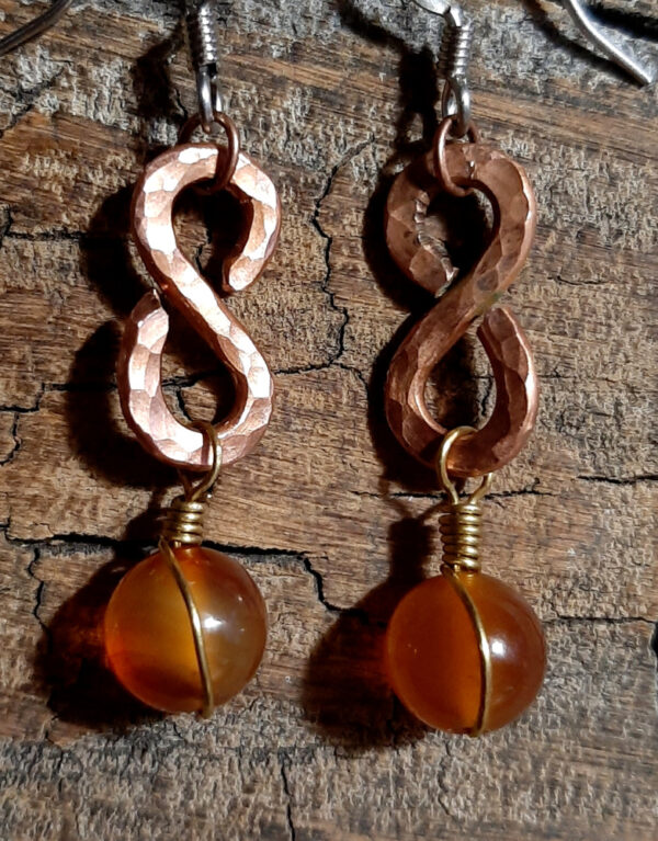 Each earring is a vertical infinity symbol with an amber-colored round glass bead hanging below.