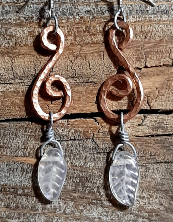 Each earring is a stylized S shape in hammered copper wire with a clear glass leaf hanging from the bottom.