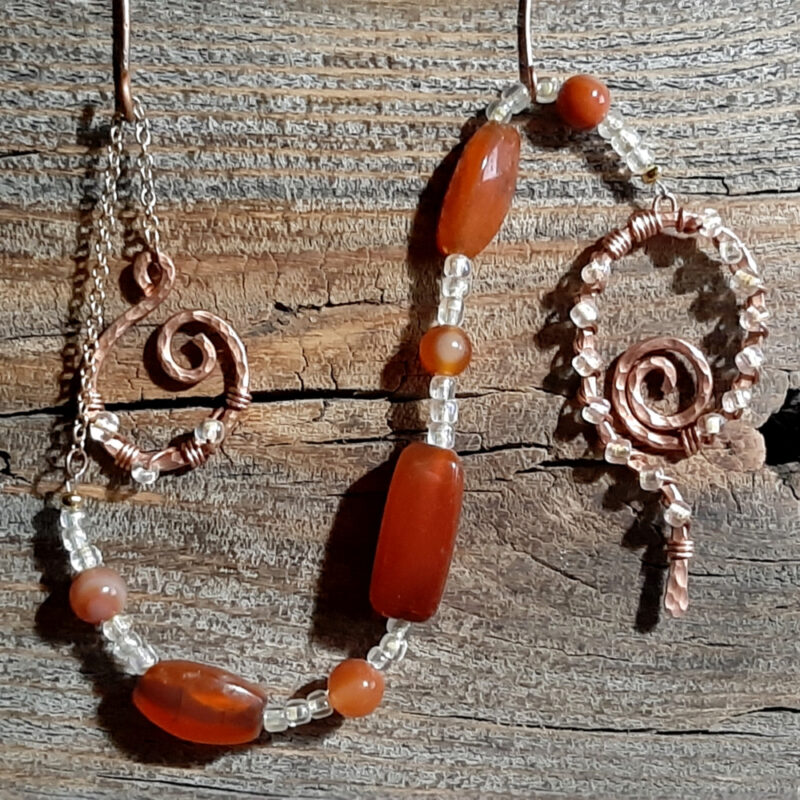 Lovely deep orangey-brown beads set off by lil glass beads that are MOSTLY clear but have just a tint of yellow, plus a pointer & finger loop of hammered copper wire.