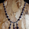 This necklace has alternating white and purple beads, with three short lengths of the same beads dangling from the center front.